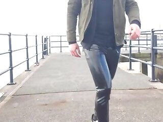 A guy is walking outside in rubber pants.